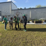 People gardening near a large warehouse